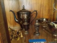 Photo showing sterling silver teapot, salt and pepper shakers, small condiment tray, and a couple of small brass bells.