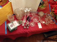 Several clear crystal dishes of various shapes including bowls, a basket-shaped dish, a footed compote, and a flower-shaped dish with etched patterns, alongside marble figurines and small decorative items.