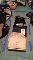 Full view of the collection of varied vintage purses with beaded and sequined detail on display on a bed.
