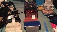 Photo of 7 assorted handbags, clutches, wallet and travel shoe jewelry bags laid out on a bed.