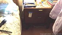 Full view of the walnut nightstand next to a bed showing two drawers and partial top surface with a phone and various small items.