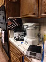 Photo of the countertop showing Original Crockpot with floral pattern, white Cuisinart yogurt ice cream maker, and Weight Watchers cooking scale.