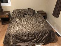 Double bed made with brown patterned bedding and two wooden nightstands placed on each side