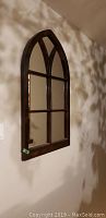 Photo of tall arched wooden framed mirror hung on wall