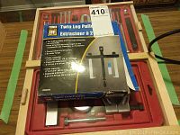 Top view of Power Fist Twin Leg Puller box and partial view of red storage tray with puller parts inside wooden frame.