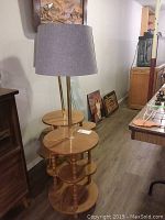 Two matching retro wooden side tables with integrated floor lamps and gray fabric shades in a room setting.
