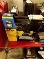 View of the PowerFist product box showing the stapler nailer image and branding.