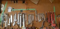 Wide view of multiple wrenches hanging on pegboard including monkey wrenches and open-end wrenches