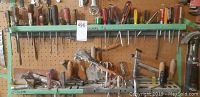 Long view of pegboard with screwdrivers on upper shelf, a framing nailer, and various hand tools on bottom shelf.