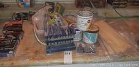 Overview of whetstones and miscellaneous items including paint cans and nail packages on table