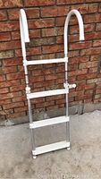 Front view of the three-step boat ladder showing white curved handles and white textured steps attached to aluminum frame.