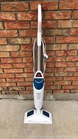 Full upright view of the Bissell steam cleaner against a brick wall background.