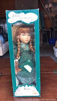 Ceramic Anne of Green Gables doll in original green box showing front with clear window and the doll inside wearing a green dress.