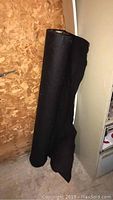 Black landscape underlay fabric rolled and standing against wall