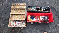 Fishing tackle box on the left with multiple compartments containing colorful fishing lures and assorted small fishing accessories. Red plastic tool box on the right with tools and components.