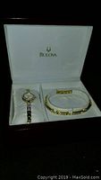 Bulova branded box open showing the watch and bracelet set resting on cushions inside the box.