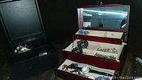Two jewelry boxes displayed open with various costume jewelry and watches inside.