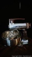 Sunbeam Mixmaster stand mixer with stainless steel bowl and beaters attached, showing overall unit and accessories.