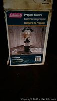 Photo of the original packaging box for a Coleman propane lantern showing front label with picture and text in multiple languages.