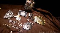 Photo showing several belt buckles with skull and other designs along with assorted vintage and decorative keys.