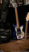 Full view of FirstAct electric guitar with blue distressed body next to black ChromaCast gig bag.