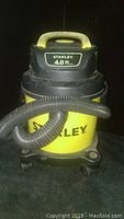 Front view of the yellow and black Stanley wet dry vacuum showing 4.0 peak HP label and attached hose.