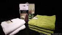 Full view of the bath set including folded green bath towels, white towels, and boxed shower curtain set with leaf pattern and 13 pieces.