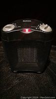Front view showing the Holmes branding, red power indicator light, and two silver control knobs on top of the black heater with mesh grille front.