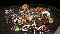 Overview of costume jewelry lot with assorted beaded necklaces and bracelets on black fabric background