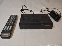 Photo showing Dreamlink T5 HD Receiver, remote control, and power adapter laid out on white surface.