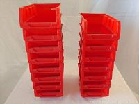 Front view of two stacks of red plastic hardware organizer bins, showing the open front and side ridges for stacking.