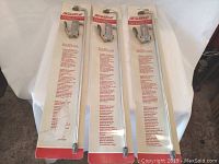 Three new Dynaflo air guns in original sealed packages, metal silver guns with black lever handles and bent nozzles, displayed against white background.