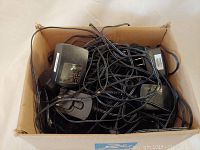 Box filled with multiple black Phitong switching power supplies tangled with cables and plugs.