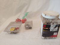 Wide view of entire hardware lot showing the large bottle with metal parts, the plastic containers with valve buttons and fittings, and bag of wire connectors.