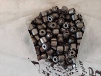 Top-down view of a bag filled with numerous small cylindrical metal bearings with central holes, metallic gray finish.
