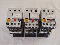 Three Eaton XTOB001CC1 relays arranged side by side showing front face with wiring terminals and adjustment dials.