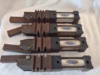 Four Destaco pneumatic clamps laid parallel, showing metal construction, visible rust, and the rectangular clamp arms connected to pneumatic cylinders with Destaco labels.