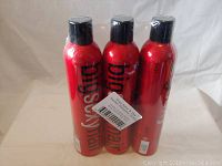 Three unopened red cans of Big Sexy Hairspray. Large black text branding visible on each can.