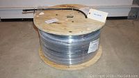 Photo showing the full wooden spool wrapped with black fiber optic cable and attached labels.