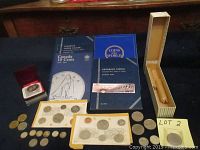 Overview of various coin books, coin sets in packaging, rolls of pennies, and loose coins arranged on a table.