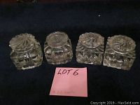 Top view of four glass ink wells with tops, showing slight chips and distinct designs