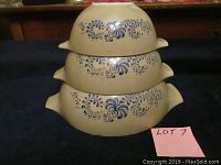 Stacked view of three Pyrex Homestead Cinderella mixing bowls seen from side showing nesting and handles with blue floral pattern.