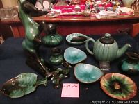 Various Blue Mountain Pottery items including horse figurine, teapot, small vases and bowls arranged on a blue cloth