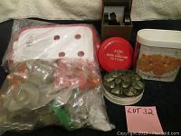 Group photo of assorted vintage cookie cutters and kitchen tins, some in plastic bags, with a white plastic kitchen container with holes