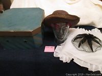 Wide shot including the two hats, the vintage striped hat box, and a glass head model (not included) with brown wide-brimmed hat.