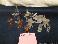 All 10 glass elephant figurines displayed together on dark fabric background including clear, frosted and amber colored pieces in various sizes and styles.
