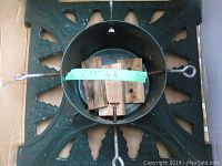 Top view of heavy-duty cast iron Christmas tree stand showing three securing eye bolts and wooden stabilizers in center.