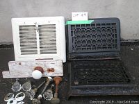 Full lot of three vintage heating registers and glass door knobs with mounting hardware on concrete surface