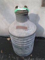 Full side view of the tall metal oil can with a capped spout, showing ribbed base and raised Imperial Oil Ltd lettering.