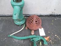 Photo showing green cast iron water pump next to rusted cast iron turtle and a lot number tag.
